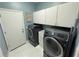 Well-equipped laundry room with modern black washer and dryer, white cabinets and blue walls at 4412 Conroy Club Dr, Orlando, FL 32835