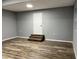 Finished basement with wood-look flooring, neutral paint, stairs, and a white door at 4900 Grand Ave, De Leon Springs, FL 32130