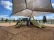 Community playground featuring slides and climbing structures under a shaded canopy, with lake views and swings in the background at 4934 Chase Ct, St Cloud, FL 34772