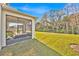 View of the backyard with a screened lanai, lush green lawn, and natural wooded area at 5237 Royal Point Ave, Kissimmee, FL 34746