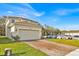 Two-story home featuring a two-car garage, brick driveway, well-manicured lawn, and neutral-colored exterior at 5237 Royal Point Ave, Kissimmee, FL 34746