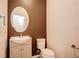 Clean and simple powder room featuring an oval mirror, vanity with storage, and a toilet at 603 Fortuna Dr, Davenport, FL 33837