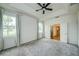 Serene main bedroom with tray ceiling, fan, carpet, and a doorway to an en-suite bathroom and walk-in closet at 603 Fortuna Dr, Davenport, FL 33837