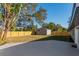 Backyard featuring a gray storage shed, wooden fence, concrete patio, and green trees, all under a clear sky at 605 Hill Ave, Ocoee, FL 34761