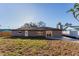 View of the backyard featuring a gray home with an attached patio and sliding glass door, surrounded by a lawn at 605 Hill Ave, Ocoee, FL 34761