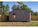 Backyard view of storage shed with a single window and door, surrounded by a wooden fence and trees at 605 Hill Ave, Ocoee, FL 34761