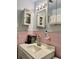 Vintage bathroom featuring pink tile, a pedestal sink, and classic white cabinets at 701 S Delaware Ave, Deland, FL 32720