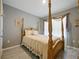 Cozy bedroom featuring a four-poster bed with floral accents and soft natural light filtering through the window at 756 Kindred Ln, Auburndale, FL 33823