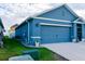 A side view of blue house featuring a two-car garage and well-maintained landscaping at 756 Kindred Ln, Auburndale, FL 33823