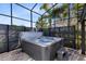 Screened-in back patio with a hot tub, privacy screen, and pavers at 8803 Peachtree Park Ct, Windermere, FL 34786