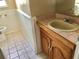 Bathroom with a sink, wood vanity, mirror, tiled floors, and a toilet at 12314 Virginia Dr, Leesburg, FL 34788