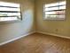 Cozy bedroom with laminate floors, two windows, and neutral-colored walls at 12314 Virginia Dr, Leesburg, FL 34788
