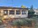 Rear exterior featuring three windows, air conditioning unit and overgrown landscaping at 12314 Virginia Dr, Leesburg, FL 34788