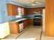 Kitchen with oak cabinets, black appliances, tile floors, and blue walls at 12314 Virginia Dr, Leesburg, FL 34788