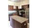 Modern kitchen featuring stainless steel appliances, island, granite countertops and wooden cabinetry at 12521 Floridays Resort Dr # 206F, Orlando, FL 32821