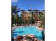 An aerial view of a community pool area on a sunny day features palm trees and many lounge chairs at 12521 Floridays Resort Dr # 206F, Orlando, FL 32821