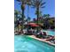 A large community swimming pool is bordered by many lounge chairs and tropical palm trees at 12521 Floridays Resort Dr # 206F, Orlando, FL 32821