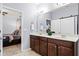 Bathroom with double sinks, dark wood cabinets, and a doorway leading to the bedroom at 15506 Tidal Cove Aly, Winter Garden, FL 34787