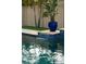 Close-up of pool water feature with blue planters on travertine tile detail at 16259 Misty Hills Ave, Winter Garden, FL 34787