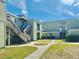 Apartment complex featuring green siding, stairways, and a well-maintained lawn with a walkway on a sunny day at 166 Scottsdale Sq # 166, Winter Park, FL 32792