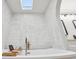 Bathroom with skylight featuring a modern soaking tub, white textured tile, and a double vanity at 2294 Lakeview Ave, Clermont, FL 34711