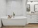 Bright bathroom featuring a modern soaking tub, white textured tile, and a double vanity at 2294 Lakeview Ave, Clermont, FL 34711