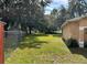 View of the grassy, fenced backyard with mature trees, offering privacy and space at 231 Cranbrook Dr, Kissimmee, FL 34758