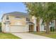 Inviting two-story home featuring a manicured lawn, cream-colored paint, and a convenient two-car garage at 2362 Blossomwood Dr, Oviedo, FL 32765