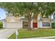 Charming two-story home with a red double door, a well-maintained lawn, and large shade tree at 2362 Blossomwood Dr, Oviedo, FL 32765