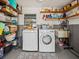 Functional laundry room includes washer, dryer, utility sink, and ample shelving for storage, complete with patterned rug at 2405 Janet St, Kissimmee, FL 34741