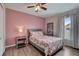 Cozy bedroom features a ceiling fan, wood-look flooring, stylish bedside table and bright window at 2604 Hollow Ln, Leesburg, FL 34748