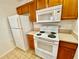 Kitchen with white appliances, wood cabinets, and a ceramic tile floor at 2605 Gala S Rd # 103, Kissimmee, FL 34746