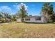 An expansive lawn surrounds this single story home with white siding and mature trees on a sunny day at 33 Sunset Dr, Debary, FL 32713