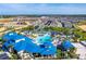 Aerial view of a resort-style community pool with lazy river, waterslides, beach volleyball, and extensive lounging areas at 3373 Lilac Way, Davenport, FL 33897