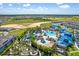 Aerial view of a resort-style community pool with lazy river, waterslides, beach volleyball, and extensive lounging areas at 3373 Lilac Way, Davenport, FL 33897