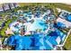 Aerial view of a resort-style community pool with lazy river, waterslides, beach volleyball, and extensive lounging areas at 3373 Lilac Way, Davenport, FL 33897