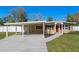 Inviting single-story home featuring a convenient carport, well-maintained lawn, and cheerful red door at 382 Frances Ave, Casselberry, FL 32707