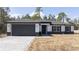 Charming single-story home with gray driveway, dark gray garage door and black shutters at 41915 Aspen St, Eustis, FL 32736