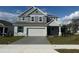 Charming two-story home featuring gray siding, a two-car garage, and a well-manicured lawn at 4972 Lyric Dr, Mascotte, FL 34753