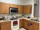 Well-lit kitchen featuring a white stovetop, microwave, and wooden cabinetry at 504 Delido Way, Kissimmee, FL 34758