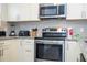 Close-up of stainless steel oven and overhead microwave in a kitchen with white cabinets and granite countertops at 5356 Diplomat Ct # 105, Kissimmee, FL 34746