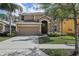 Charming two-story home featuring a well-manicured lawn, mature trees, and a two-car garage at 620 Orange Cosmos Blvd, Davenport, FL 33837