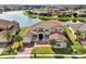 Aerial view of a beautiful stucco home with a red roof, well-manicured lawn and lake views at 890 Spinnaker Way, Kissimmee, FL 34746