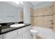 Bathroom featuring a white sink, black countertop, framed mirror, and a tiled shower and tub at 890 Spinnaker Way, Kissimmee, FL 34746