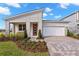 Modern home with a red front door, white trim, a brick driveway, a 2-car garage, and manicured landscaping at 9292 Sea Pine Ave, Orlando, FL 32832