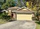 Charming home featuring a two-car garage, light yellow paint, and a well-maintained front yard with mature trees at 1011 Piedmont Oaks Dr, Apopka, FL 32703