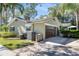 Exterior view of a house showing the garage, air conditioning units, trash cans, and a side yard at 11 Stone Gate S, Longwood, FL 32779