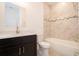 Bathroom featuring a bathtub with marble-look tile surround, dark cabinets, and a toilet at 16893 Sw 17Th Ter, Ocala, FL 34473
