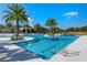 Expansive community pool with clear waters, palm trees, and various seating options under a clear sky at 2116 Limestone Trl, Kissimmee, FL 34747
