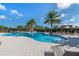 Community pool with sparkling water and a view of palm trees, lounge chairs, and shade structures at 2116 Limestone Trl, Kissimmee, FL 34747